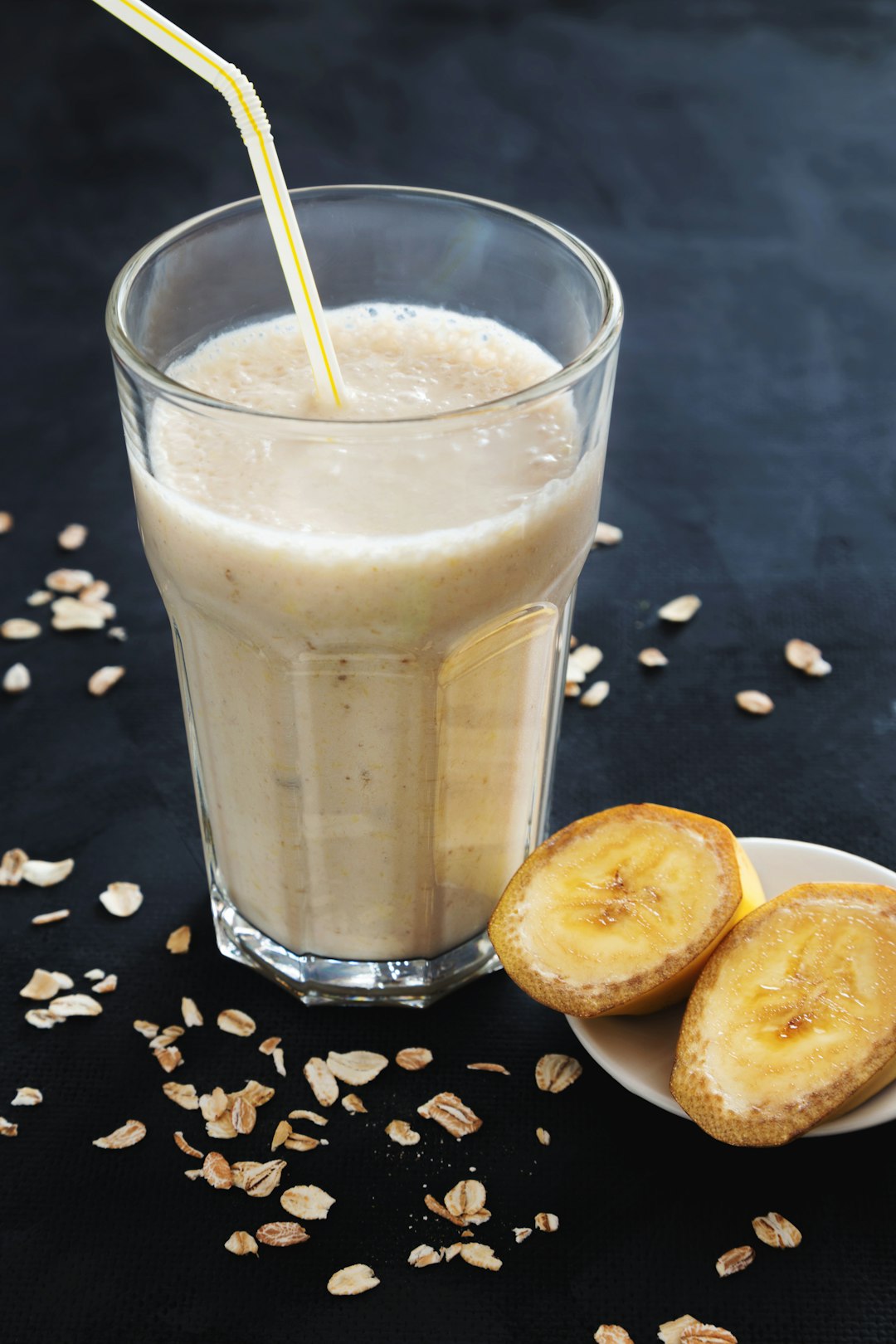 Banana smoothie in a tall glass with sliced bananas