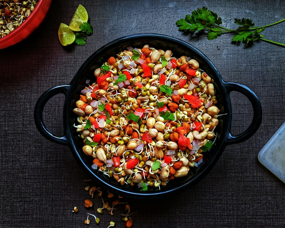 Sprouts chaat with tomato, onion and coriander in a black bowl